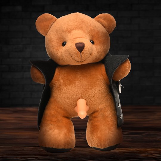 A plush brown teddy bear wearing a black vegan leather jacket, holding it open to reveal a light-colored dong, with a cheeky grin on its face.