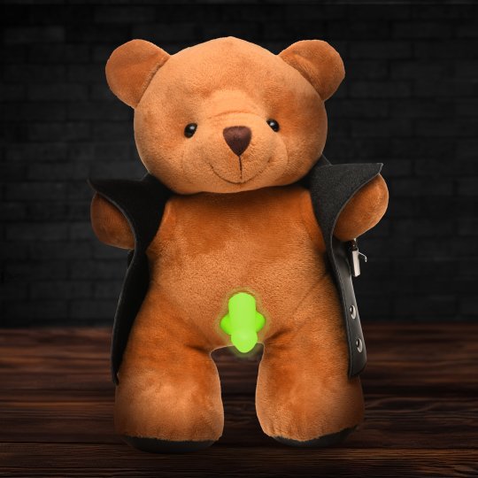 A plush brown teddy bear wearing a black vegan leather jacket, holding the jacket open to reveal a glow-in-the-dark dong, with a cheeky grin on its face.