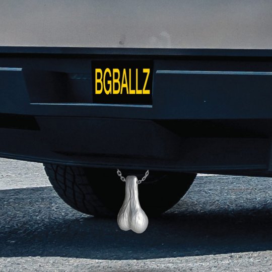 Image of a pair of extra-large fake truck nuts hanging from a car hitch, designed as a humorous gag gift, showcasing their silver color and oversized, wrinkly appearance.