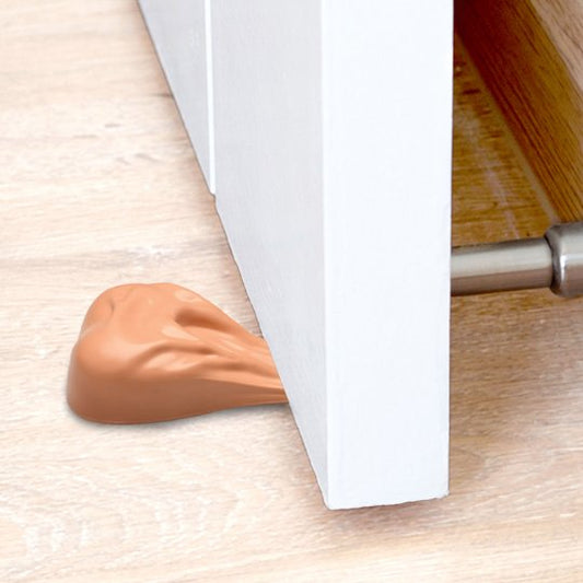 Big Big Balls Door Stop resting against a closed door, showcasing its exaggerated ball sack shape and non-slip base made of light-colored phthalate-free silicone.