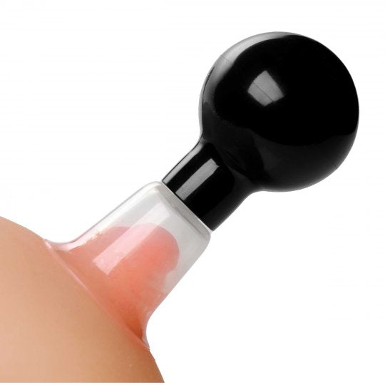 Clear and black See-Tru Nipple Boosters with a suction bulb, placed on a surface, showcasing their transparent chambers and dimensions.