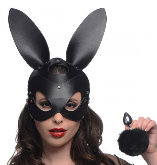 A black rabbit mask with long ears, paired with a black butt plug featuring a fluffy tail, set against a soft background, highlighting the sensuality and playful nature of the accessories.