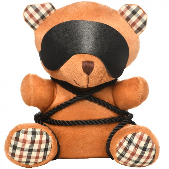 A cute brown bondage bear with silky ropes tied around its body and a removable vegan leather blindfold, measuring 9 inches long, sitting on a soft surface.