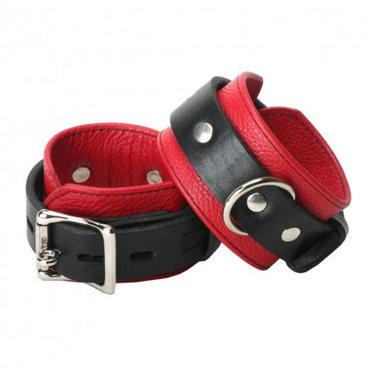 Black and red locking cuffs made of red leather with black reinforced stitching, featuring a locking buckle and D-ring for attachment, displayed on a neutral background.